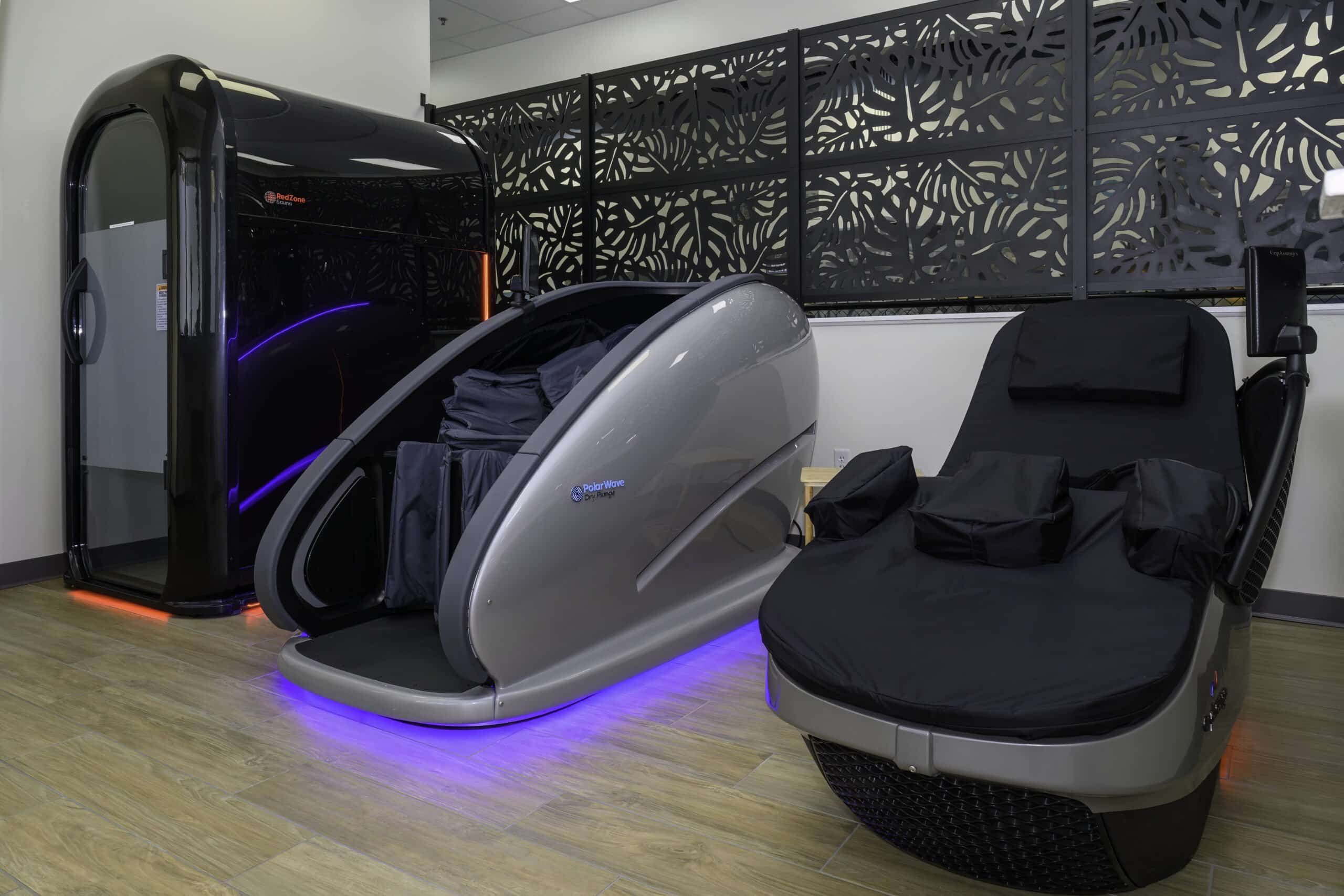 RallyWell Wellness Recovery Club amenities: infrared sauna pod, cold-plunge pod, and massage chair