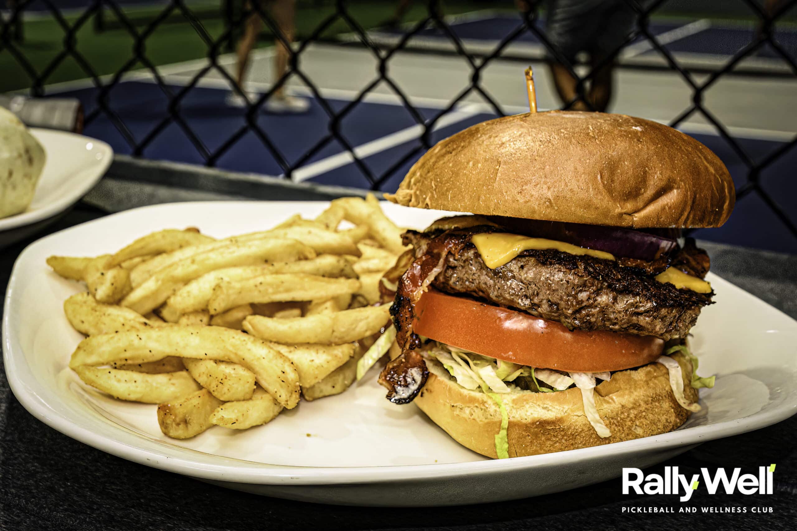 Bacon cheeseburger with fries served courtside at RallyWell