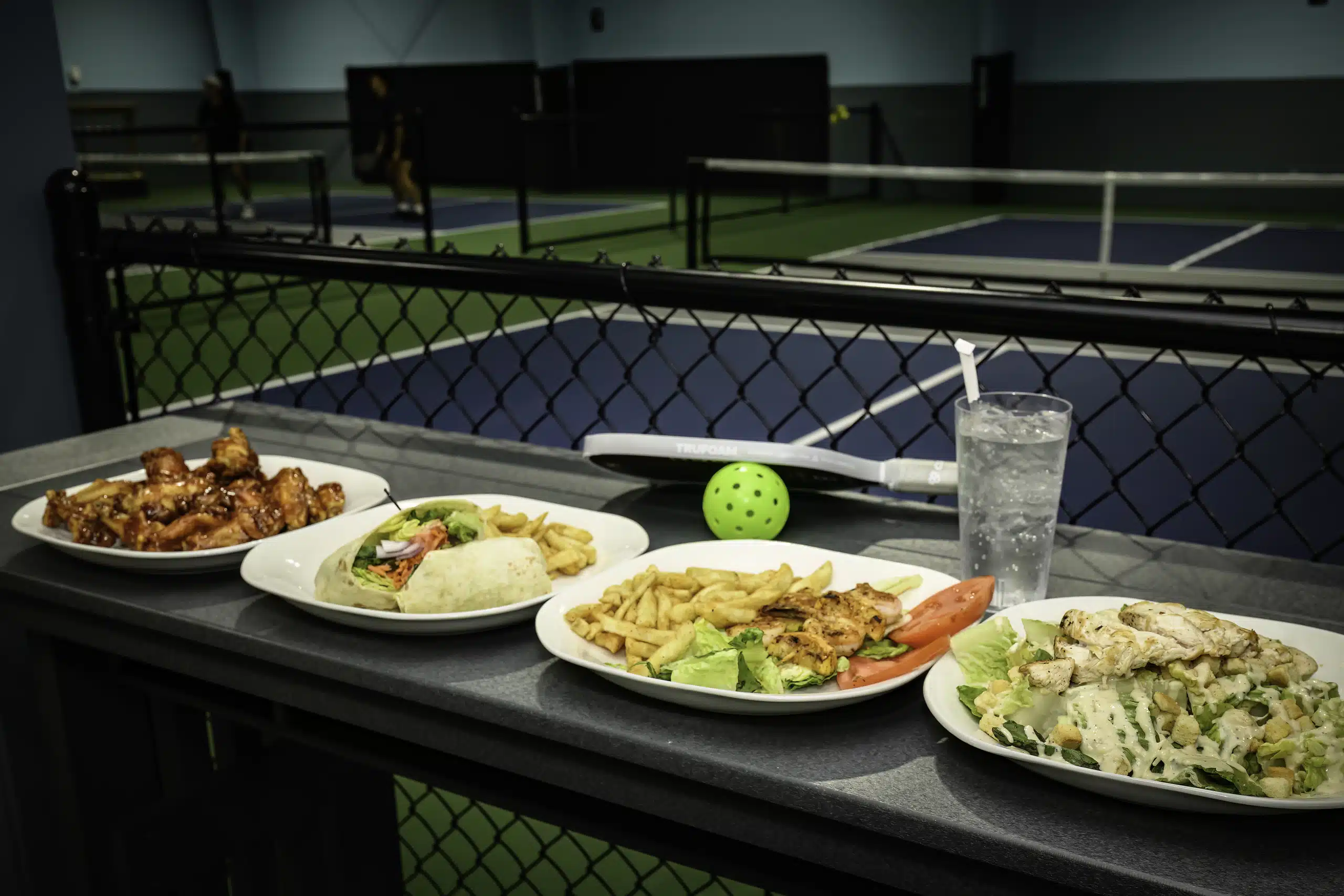 Plates of food served courtside on a pickleball net at RallyWell