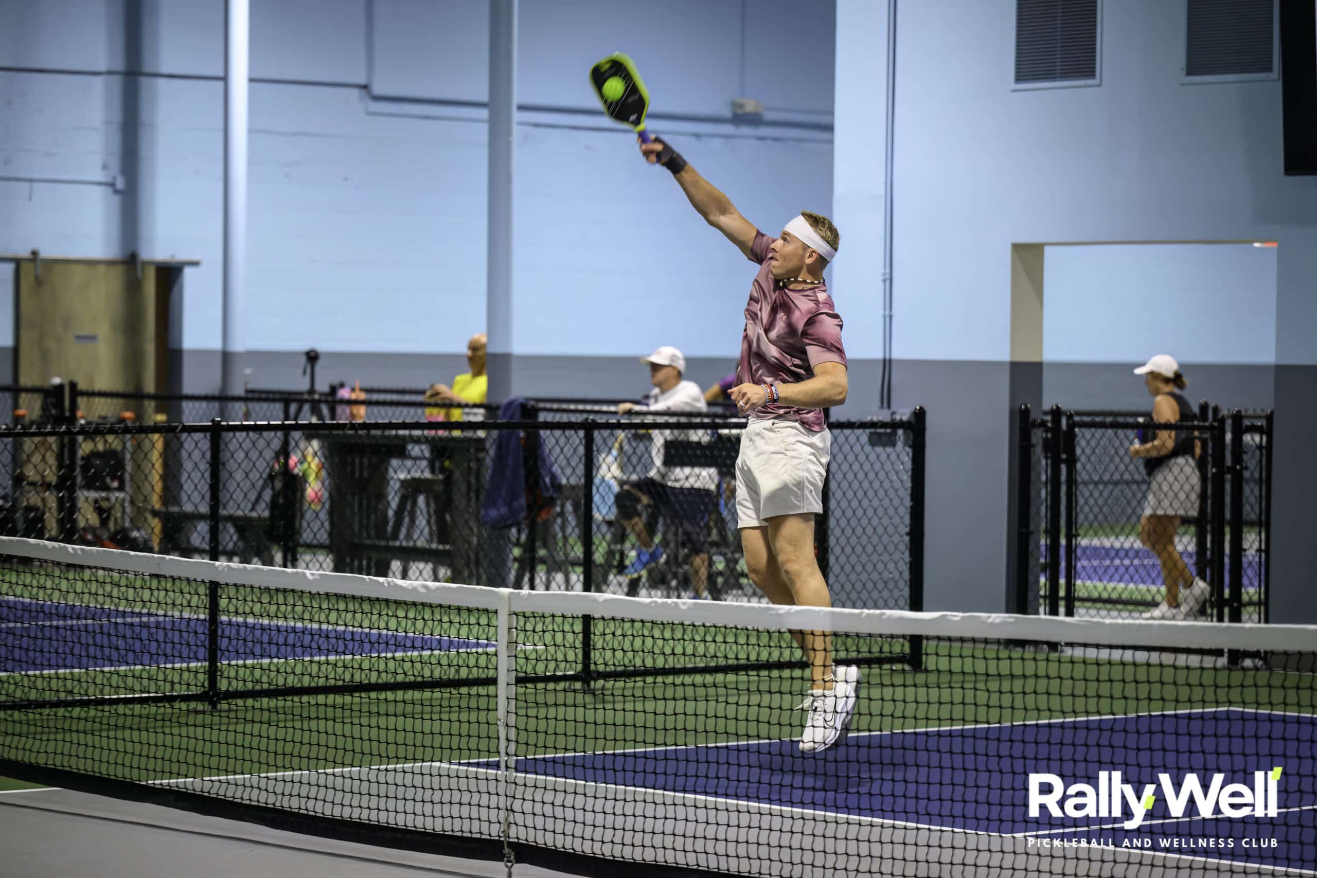 RallyWell player jumping to smash the ball at the net during a match